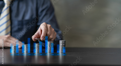 business growth idea a pile of coins and a blue piggy bank placed in front of a businessman with a financial graph