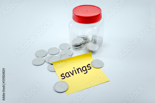 savings, scattered coins and in plastic jar with sticky note that says savings