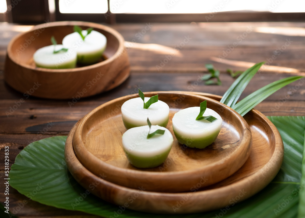 Talam Cake or in indonesia called kue talam with pandan leaves serves on wooden plate, selective focus image and blurred background. Talam Cake or in indonesia called kue talam with pandan leaves serves on wooden plate, selective focus image and blurred background.