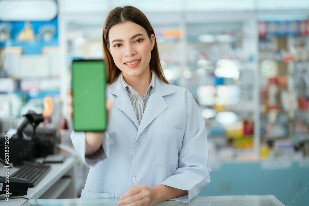 Young pharmacist standing smiling looking at the camera holding a phone in front of a green screen