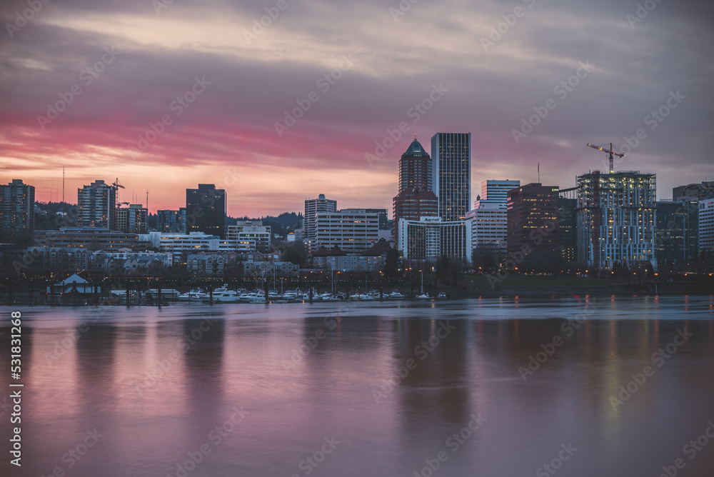 Fototapeta premium The downtown city of Portland Oregon reflecting over the Willamette River waterfront at sunset