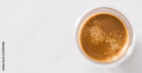 Freshly brewed coffee in a glass cup on a white background  top view  central composition  banner