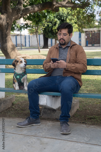 young man in a park walking his dog chating on cell