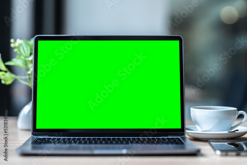 Obraz na płótnie Mockup of laptop computer with empty screen with coffee cup and smartphone on table of the coffee shop background,Green screen w salonie