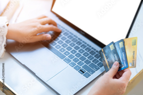 Close-up of freelance people business female Hand holding Credit cards casual working using with laptop computer empty screen in coffee shop like the background,Online payment shopping concept