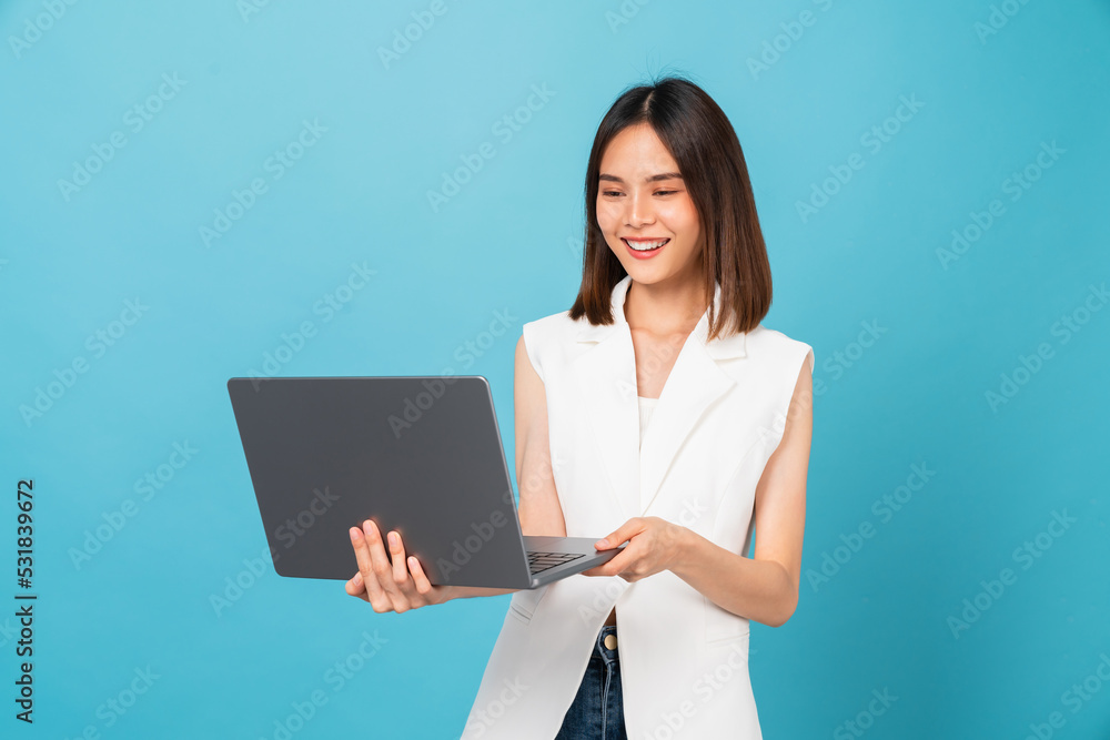 Studio shot of cheerful beautiful Asian woman holding laptop with typing on keyboard on blue background. Studio shot of cheerful beautiful Asian woman holding laptop with typing on keyboard on blue background.