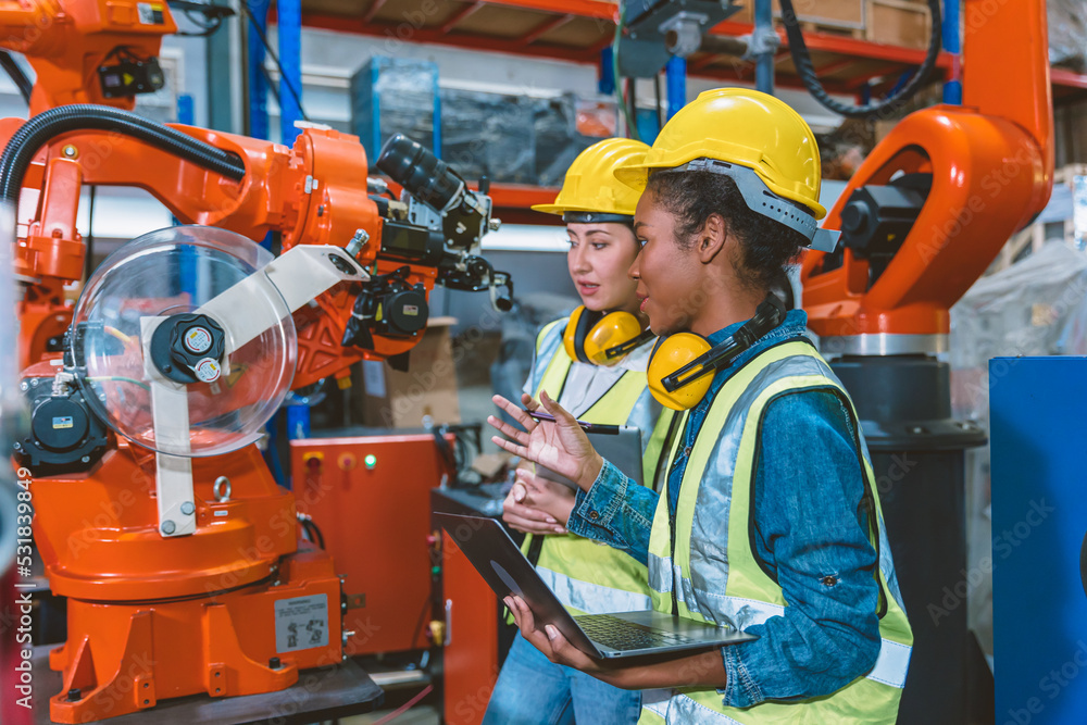 © Quality Stock Arts - Women engineer worker working team training together at work in modern advanced robot welding machine factory.