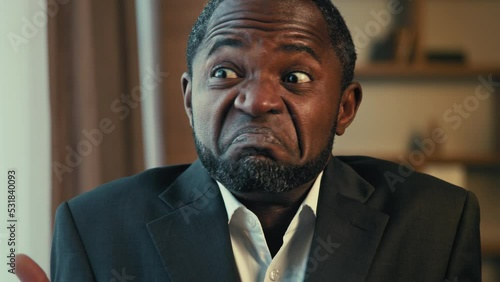 Portrait puzzled undecided adult african american businessman shrugging shoulders don't know answer confused man looking at camera standing indoors demonstrating doubt gesture incertitude sign shrugs