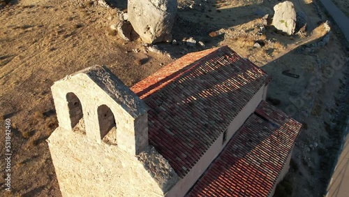 Aerial round drone flight around a romanic slyle church in Gormaz, Soria, Spain. Bult next to a huge rock. Recorded just before sunset with a warm light. photo