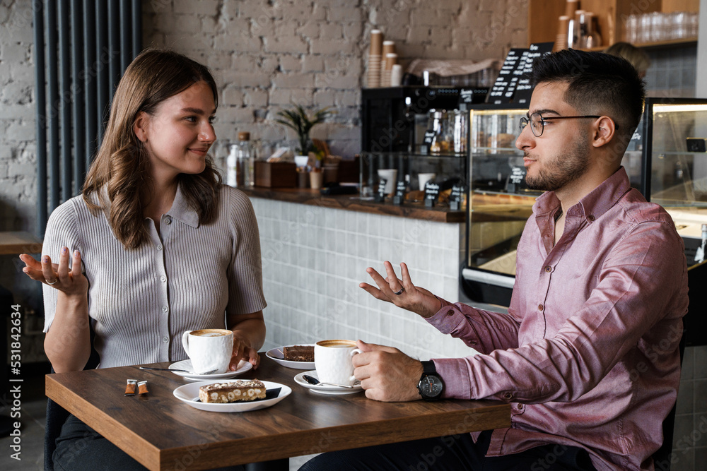 Shot of woman and man talking drinking hot coffee in coffee bar. Shot of woman and man talking drinking hot coffee in coffee bar.