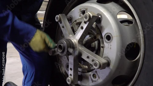 mechanic man balancing a car wheel on an automated machine. Technician man working with modern wheel balancing tool in garage. Seasonal tire changing time.