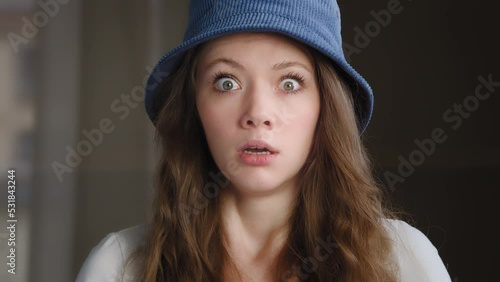 Portrait amazed surprised pretty caucasian girl looks at camera wide open eyes in surprise feeling horror fear afraid close-up young startled woman exhales with relief smiling laughing posing indoors
