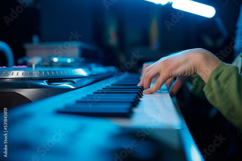 Closeup of keyboardist musician in neon light recording studio photo