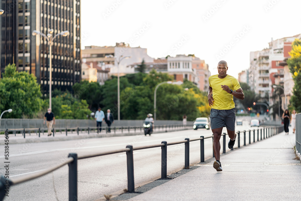 African American sportsman jogging on sidewalk in the city outdoors