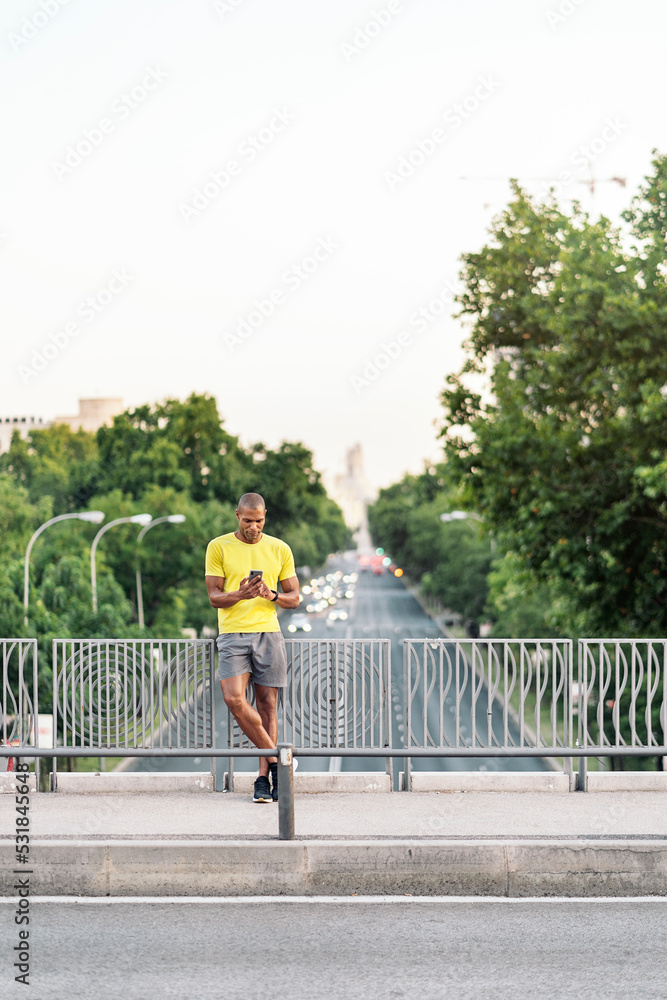 Sportsman using cellphone on sidewalk in the footbridge outdoors