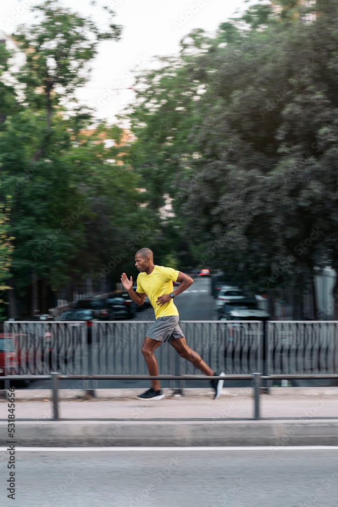 Adult sportsman sprinting on sidewalk in the city outdoors