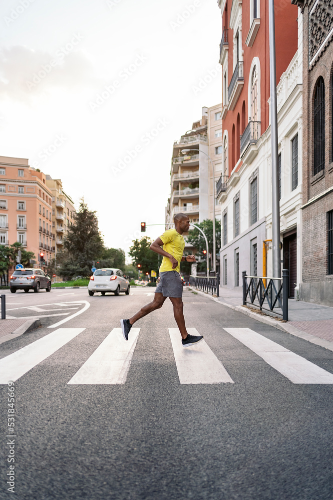 Sportsman jogging on crosswalk in the city at day