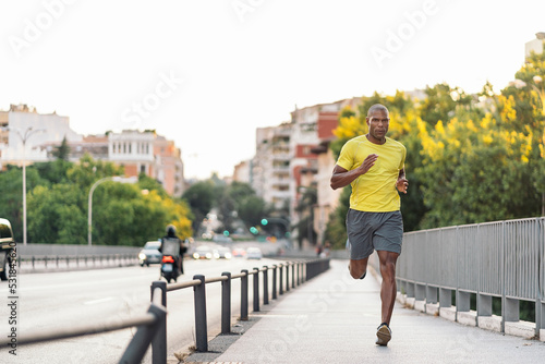 African American man jogging on sidewalk in the city outdoors © santypan