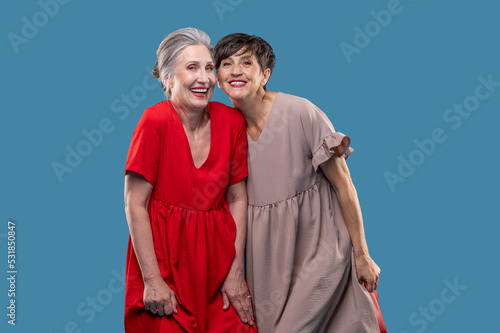 Two pretty mature women in dresses looking happy