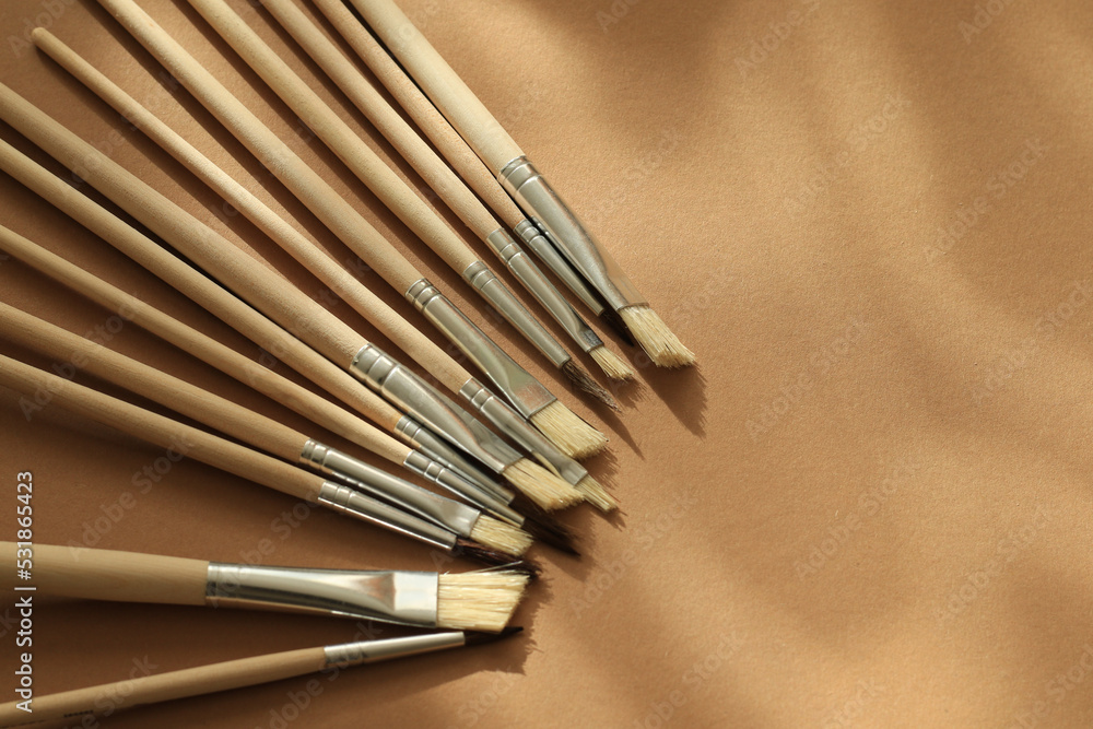 wooden aquarelle painting brush set on brown paper background with natural lights and shadows wooden aquarelle painting brush set on brown paper background with natural lights and shadows