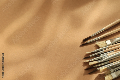 wooden aquarelle painting brush set on brown paper background with natural lights and shadows