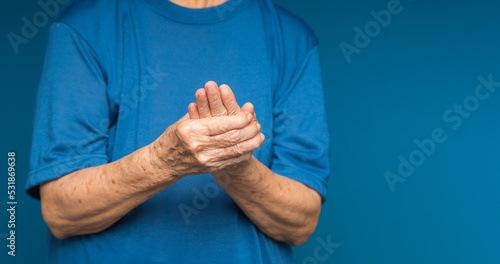 Wallpaper Mural Senior woman suffering from hand pain while standing on a blue background Torontodigital.ca