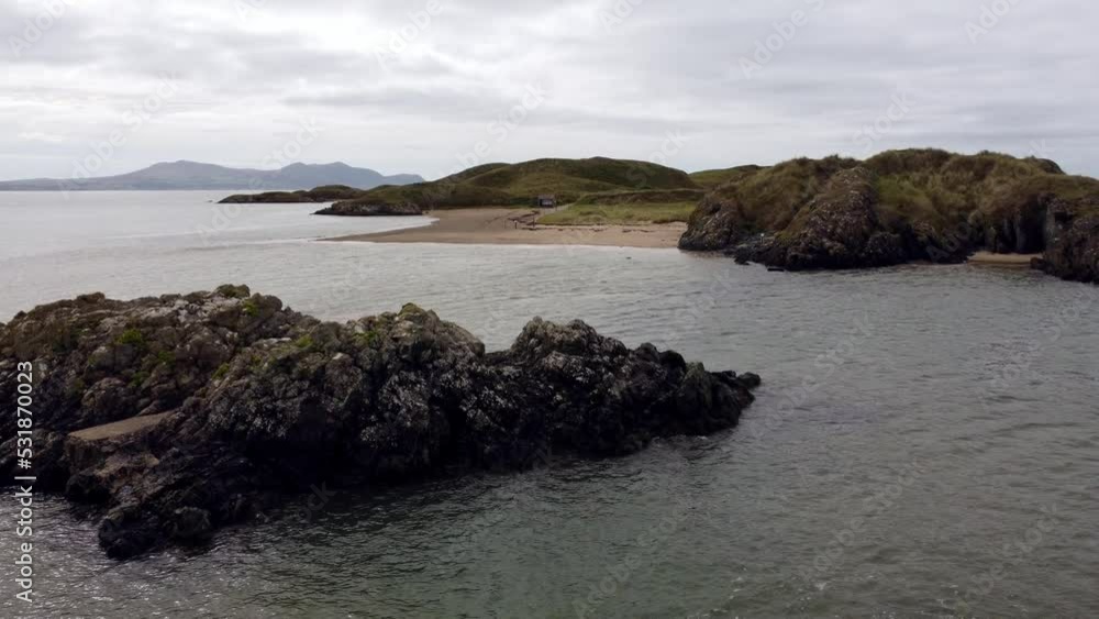Aerial view Ynys Llanddwyn island Anglesey coastal walking trail with Snowdonia mountains low flight across the Irish sea Aerial view Ynys Llanddwyn island Anglesey coastal walking trail with Snowdonia mountains low flight across the Irish sea