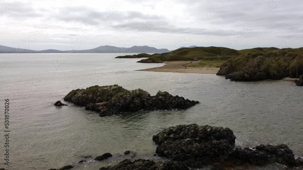 Aerial view Ynys Llanddwyn rocky island Anglesey coastal walking trail with Snowdonia mountains across the Irish sea Aerial view Ynys Llanddwyn rocky island Anglesey coastal walking trail with Snowdonia mountains across the Irish sea
