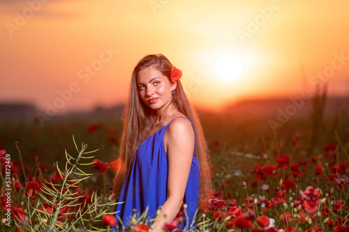 pretty young woman in poppy field with sunset landscape in background  warm sunset light