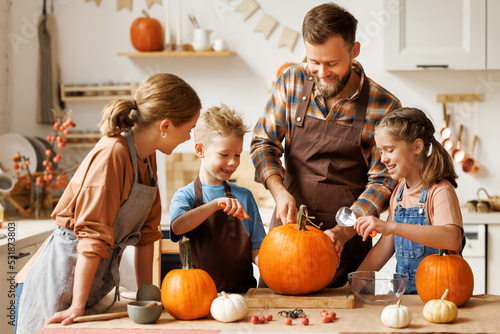 Fototapeta Happy family mother, father and kids  to remove pulp from from pumpkin while car