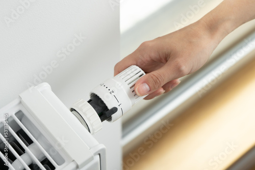 Canvas Print The woman lowers the radiator temperature to an economical heating mode