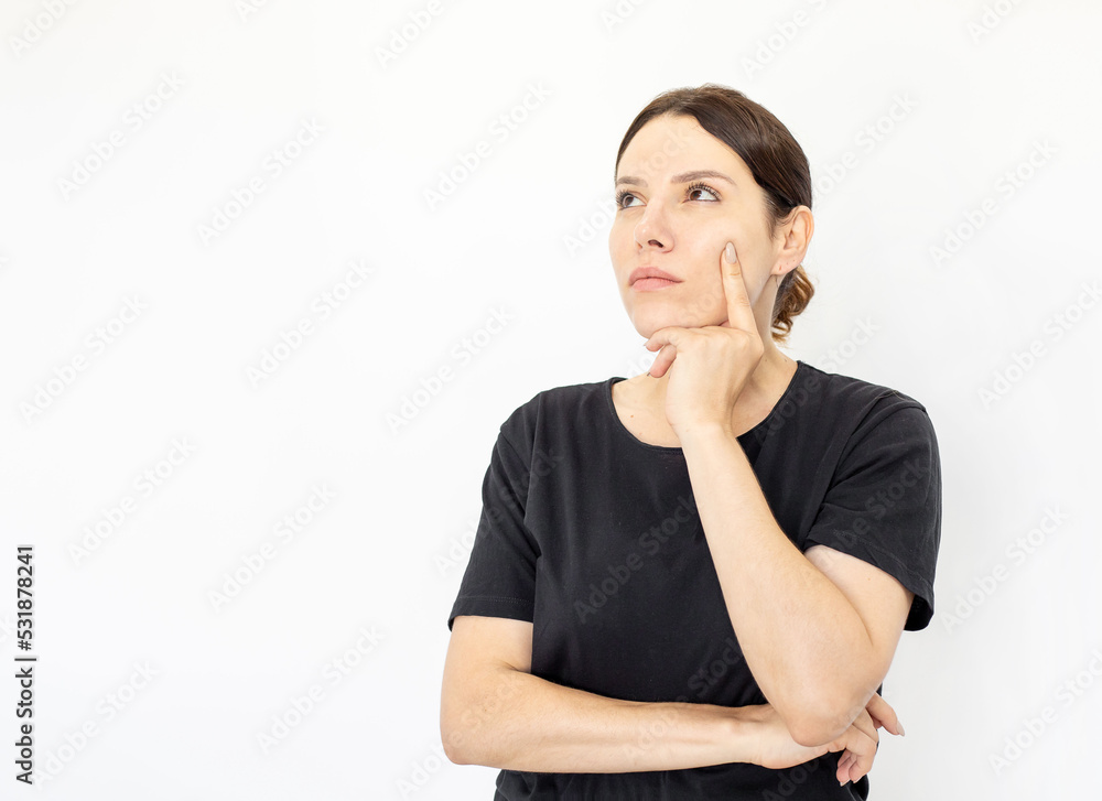 Portrait of young thoughtful woman in black T-shirt looking up. Female model thinking hard holding finger on cheek with serious face. Portrait, studio shot, thoughtfulness concept Portrait of young thoughtful woman in black T-shirt looking up. Female model thinking hard holding finger on cheek with serious face. Portrait, studio shot, thoughtfulness concept