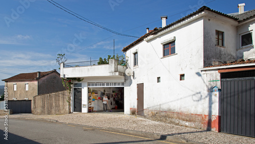 Maison blanche avec son atelier garage de réparation dans un quartier pauvre d'une ville du Portugal en été.