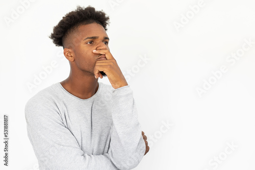 Portrait of pensive African American man looking away. Young bearded guy wearing white sweater standing with hand on chin and thinking. Solution and planning concept