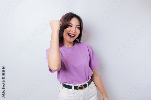 A young Asian woman with a happy successful expression wearing lilac purple shirt isolated by white background © Reezky