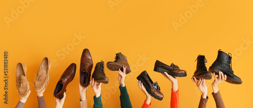 Many hands with different stylish shoes on orange background photo