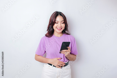 Pleased smiling Asian woman keeps hand on belly feels happy after ordering food by phone