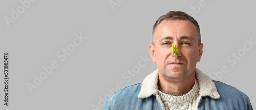 Canvas Print Ill mature man with clothespin on his nose against grey background with space fo