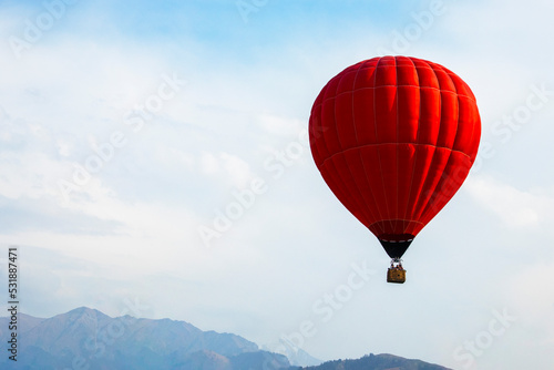 big red balloon over mountain tops in cloudy sky © Наталья Удалова