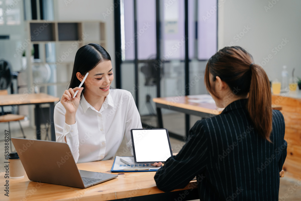 Businesswoman leading team meeting and using tablet and laptop computer with financial in coworking office. Businesswoman leading team meeting and using tablet and laptop computer with financial in coworking office.
