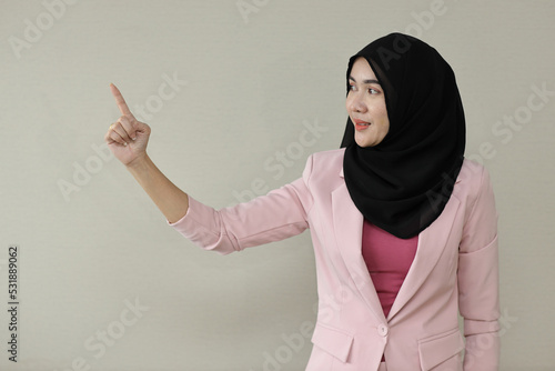 Happy smart asian business woman in muslim dress standing and pointing something with confident in studio. Isolated white background portrait beautiful face in hijab. Advertisement portrait concept