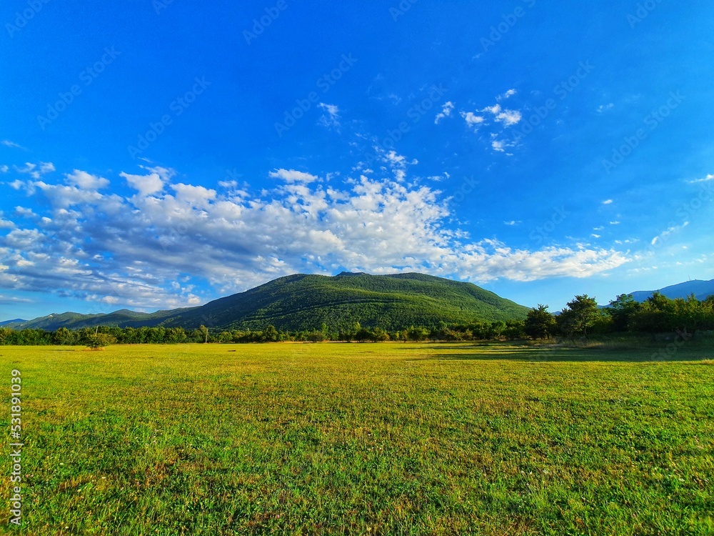 Beautiful field with blue sky and view of mountain Velebit in Croatia