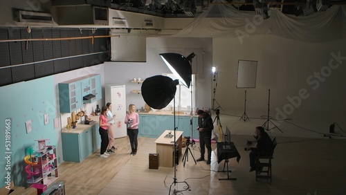 Young girls bloggers using phone making video in kitchen. Cameraman and director behind the scenes filming the process of filming and assistant clicks clapper board. Talking record lifestyle blog.