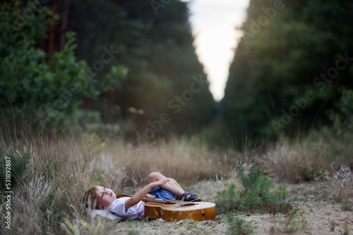 Chłopiec leży na trawie i gra na gitarze