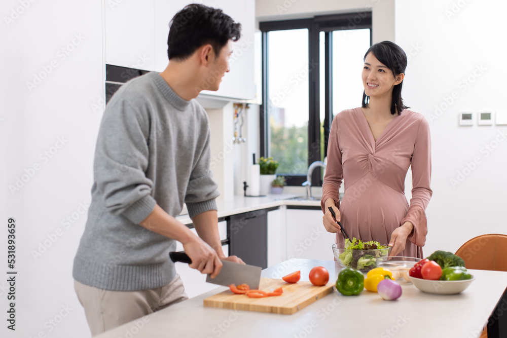 Happy pregnant woman and husband cooking in kitchen Happy pregnant woman and husband cooking in kitchen