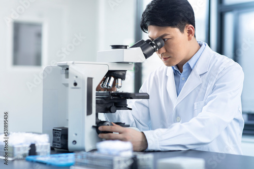 Scientist looking through a microscope photo