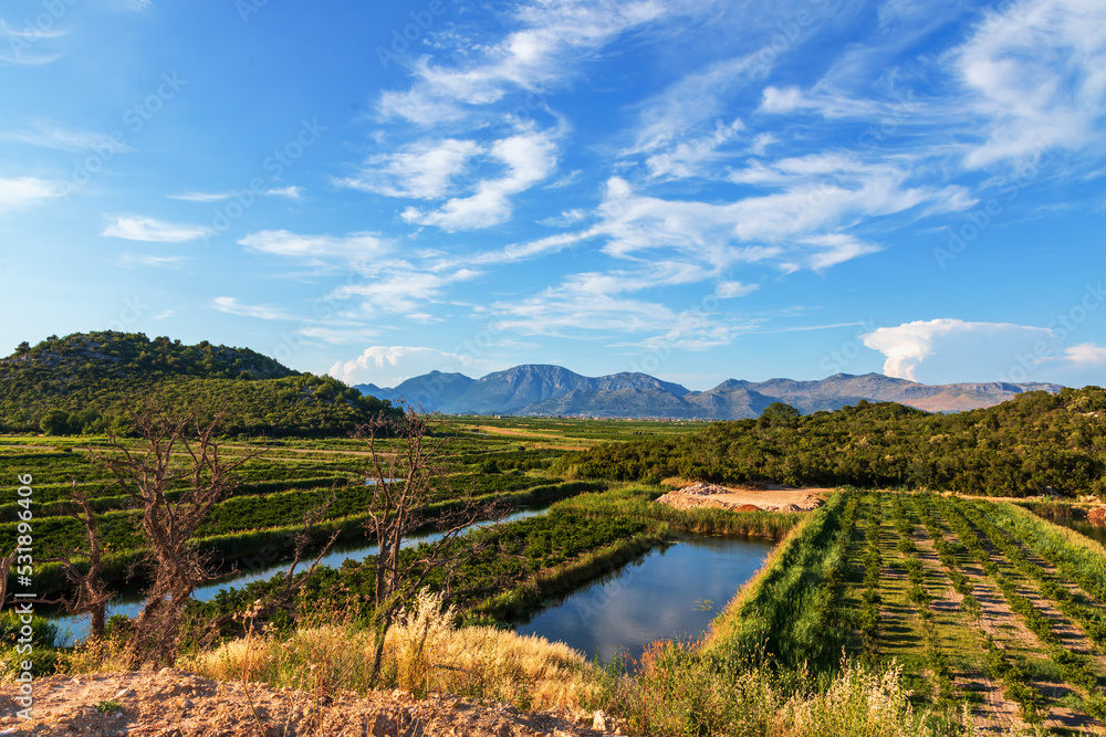 Croatian landscape. Irrigation canals in the area of Lovorje in Croatia. In the background are mountains and blue sky.