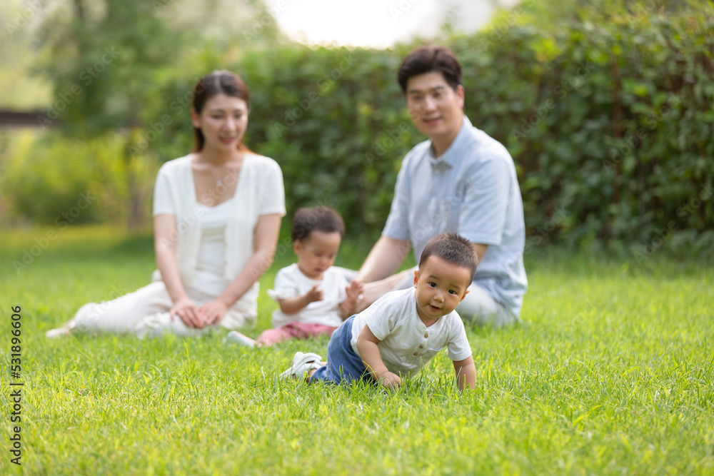 Young parents playing with twin babies in park Young parents playing with twin babies in park