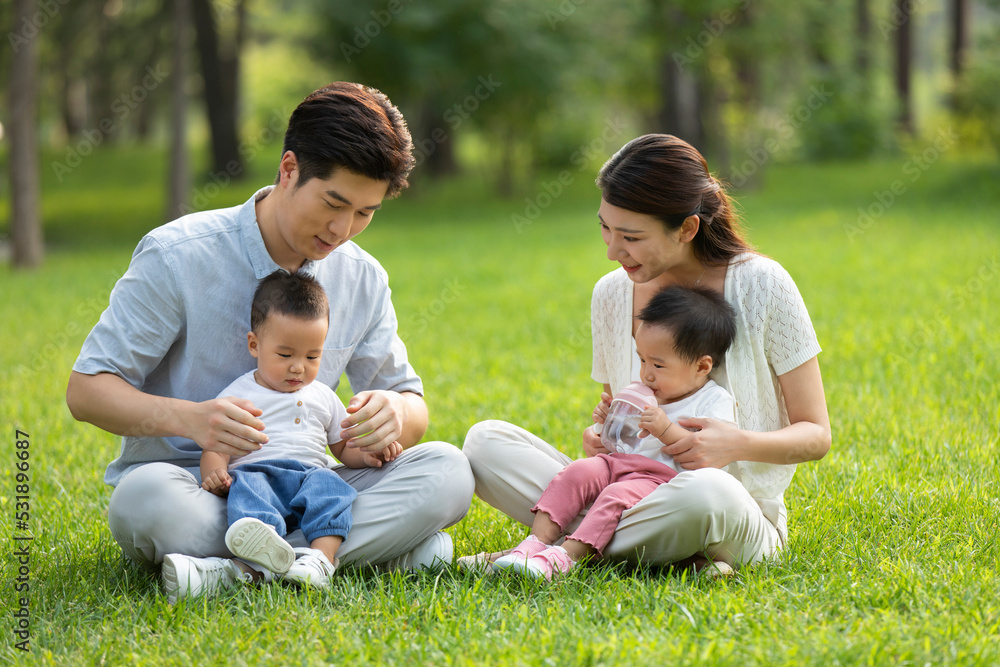 Young parents playing with twin babies in park Young parents playing with twin babies in park