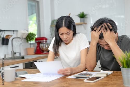 Asian couples managing debt and expenses. Husband and wife stressed over credit card bills and home electricity bills. Broke, mortgage, loan, bankruptcy, no money, bankruptcy, can't pay.